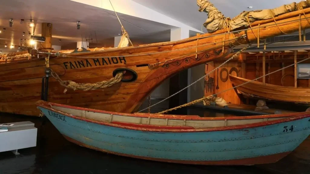 Réplica de um lugre bacalhoeiro de madeira e um dóri azul, em exposição no Museu Marítimo de Ílhavo