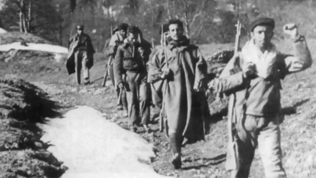 Guerrilheiros do maquis espanhol em marcha por trilho de montanha, armados com fuzis e boinas típicas, terreno com neve, anos 1940, depois da guerra civil