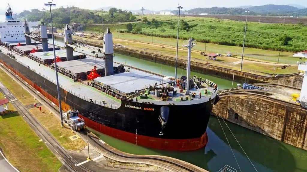 Cargueiro de casco preto e vermelho dentro de uma eclusa do canal do Panamá, entre paredes de betão. artigo estreitos