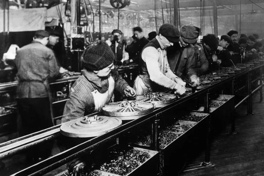 Operários montam automóveis Model T numa linha de montagem da fábrica da Ford em Highland Park, em 1913.